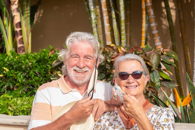 Zwei lächelnde ältere Menschen, die nach der Quarantäne zu Hause die medizinische Maske abnehmen und die Freiheit genießen