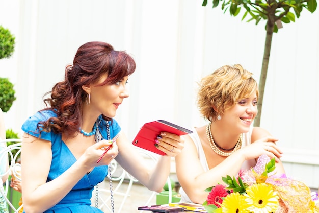 Zwei lächelnde Frauen an einem Tisch in einem Sommercafé