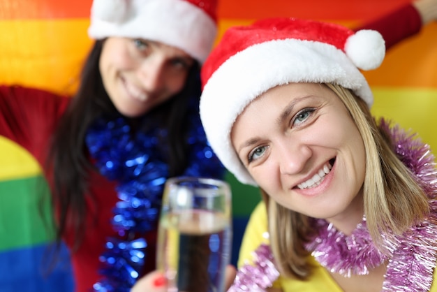 Zwei lächelnde Frauen mit lgbt Flagge, die Neujahr und Weihnachten feiern