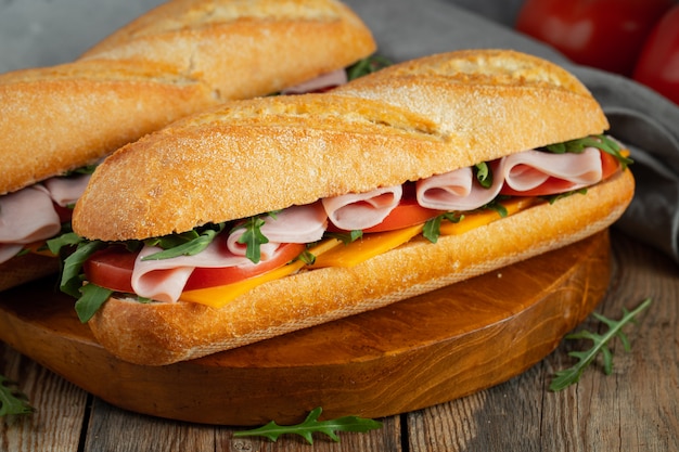 Zwei lange Baguette-Sandwiches mit Schinken und Käse.