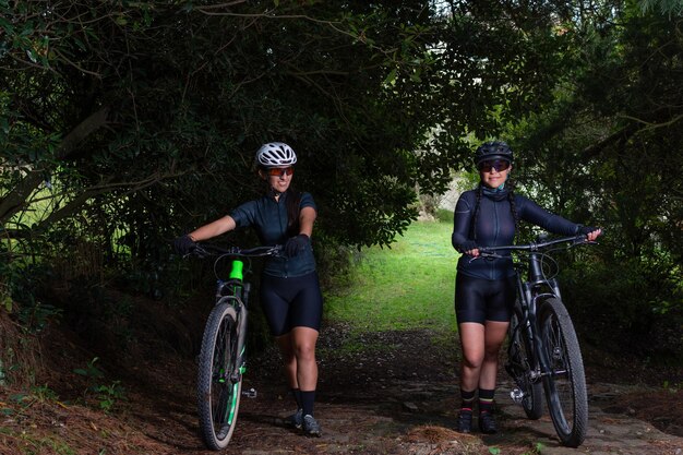 Zwei lateinamerikanische Radfahrerinnen schieben ihr Fahrrad einen Bergpfad hinunter