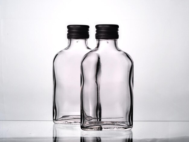 Zwei leere russische Wodka-Glasflaschen mit schwarzen Kappen isoliert auf weißem Hintergrund