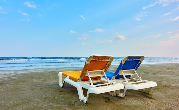 Zwei leere Sonnenliegen an einem Sandstrand am Meer am Abend, Larnaca, Zypern