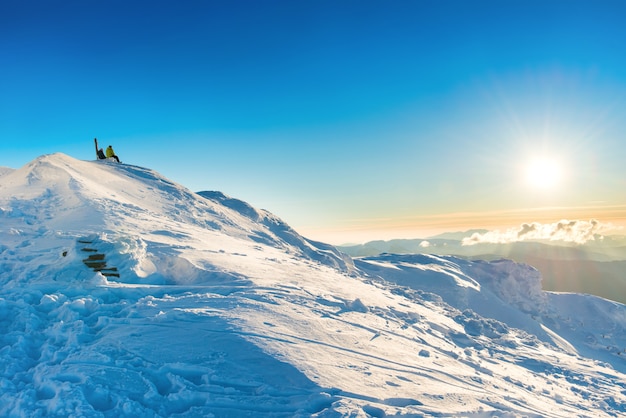 Zwei Leute, die den Sonnenuntergang von der Spitze des Winterberges mit Schnee betrachten