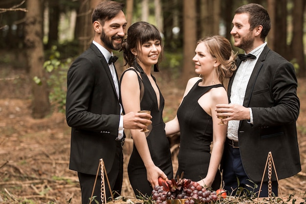 Zwei liebende junge paare in geschäftsanzügen, die ein picknick im park haben. menschen und ereignisse