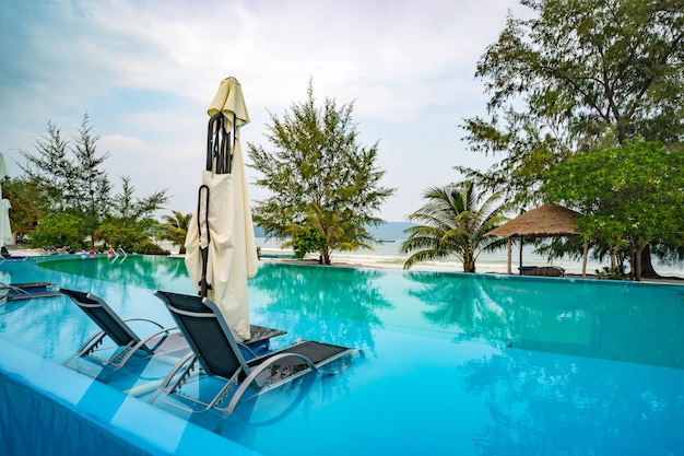 Zwei Liegestühle befinden sich in klarem Wasser im Pool am Strand Außenpool mit wunderschönem Meerblick Konzept für einen luxuriösen Aufenthalt
