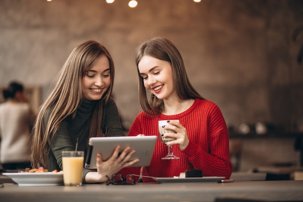 Zwei Mädchen, die auf Tablette in einem Café kaufen