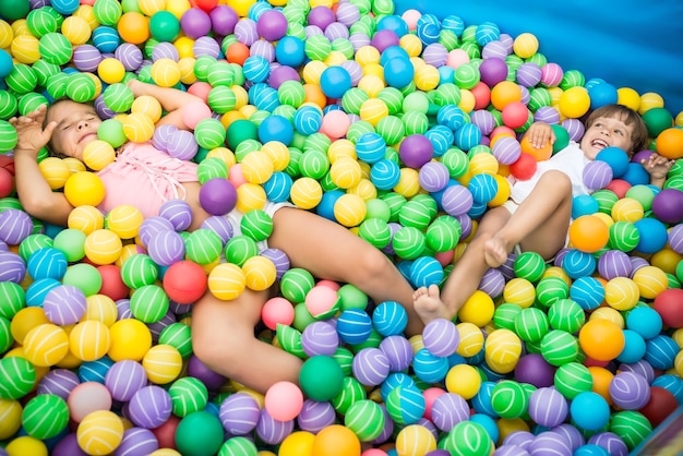 Zwei Mädchen, die im Pool mit bunten Plastikbällen im Spielzimmer spielen
