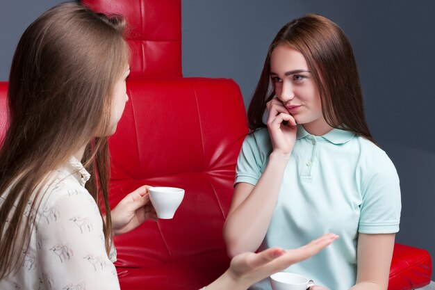 Zwei Mädchen, die Kaffee trinken und zusammen klatschen