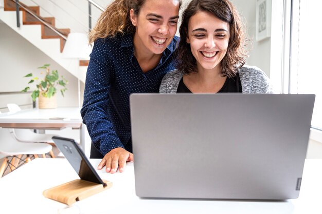 Zwei Mädchen, die lächelnd auf den Computer schauen