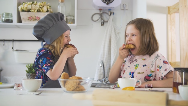 Zwei Mädchen essen Kekse mit Marmelade, die mit ihren eigenen Händen aus nächster Nähe zubereitet werden