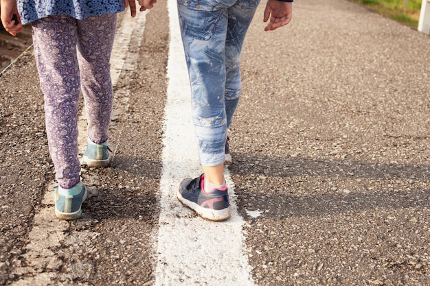 Zwei Mädchen gehen im Sommer den weißen Trennstreifen entlang