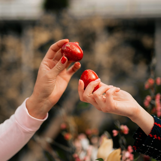 Zwei Mädchen haben einen Eierstich mit roten Ostereiern vor der religiösen Tradition des Ostertischs