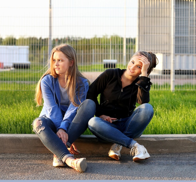 Zwei Mädchen im Teenageralter sitzen zusammen im Freien