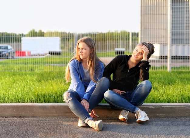 Zwei Mädchen im Teenageralter sitzen zusammen im Freien
