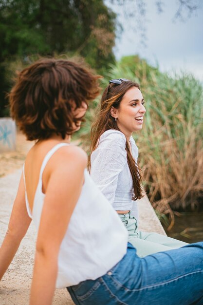 Zwei Mädchen im Teenageralter unterhalten sich und haben Spaß Sie starren auf den Fluss Pflanzen im Hintergrund