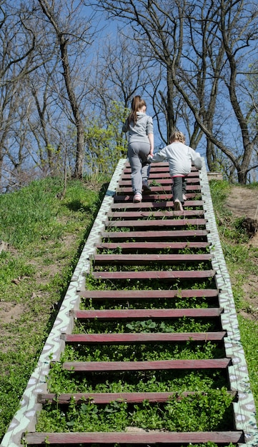 Foto zwei mädchen in grauer kleidung gehen händchen haltend die treppe hinunter