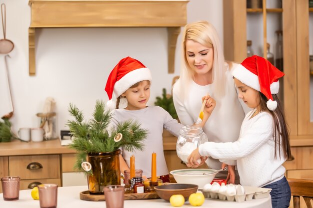 Zwei Mädchen in roten Hüten bereiten Kekse, Lebkuchen für den Neujahrsurlaub, Weihnachten vor. Kekse ausstechen.
