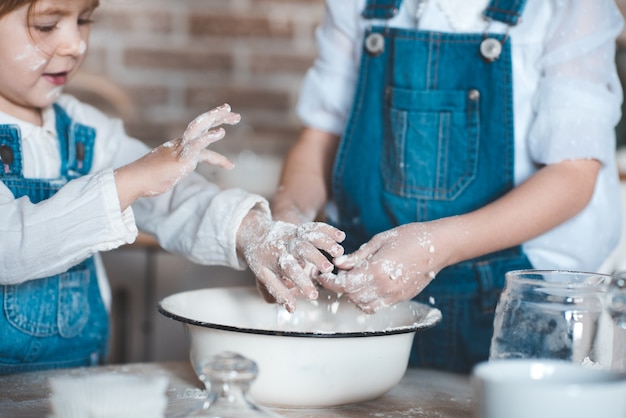 Zwei Mädchen kochen Kuchen mit Mehl in einer Schüssel in der Küche