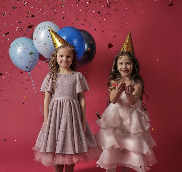 Zwei Mädchen mit Luftballons und Konfetti auf hellem Hintergrund feiern