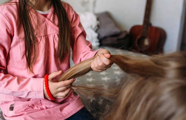 Zwei Mädchen, Schulfreunde, spielen zu Hause, machen ihre Frisur.