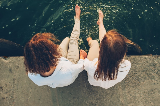 Foto zwei mädchen sitzen am pier