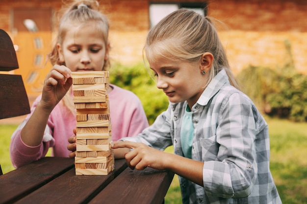 Foto zwei mädchen spielen ein hölzernes brettspiel draußen in der nähe ihres hauses