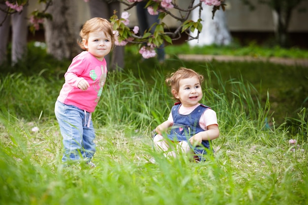 Zwei Mädchen spielen im Garten und sitzen im Gras