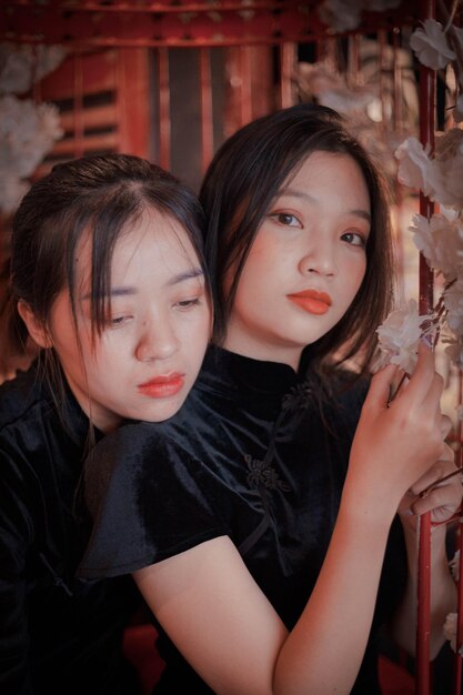 Zwei Mädchen umarmen sich, eines trägt ein schwarzes Kleid und das andere einen roten Lippenstift.