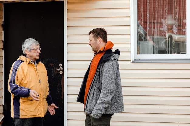 Zwei Männer, alt und jung, stehen im Hinterhof des Hauses und unterhalten sich. Älterer Vater mit erwachsenem Sohn, der Gespräche und Gespräche führt