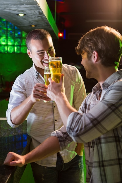 Zwei Männer, die mit Glas Bier am Bartresen in der Bar rösten