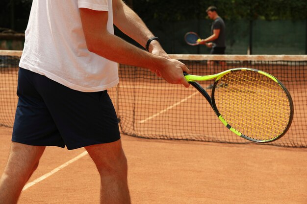 Zwei Männer, die Tennis auf Sandplatz spielen