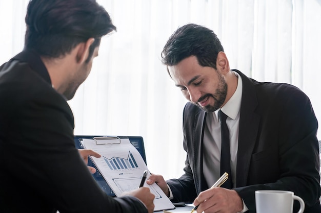 Zwei Männer in Anzügen diskutieren über einen Finanzbericht