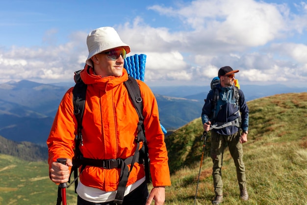 zwei Männer mit Wanderausrüstung und Rucksäcken gehen mit Trekkingstangen in die Berge