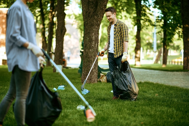 Zwei Männer sammeln freiwillig Plastikmüll in Säcken im Park