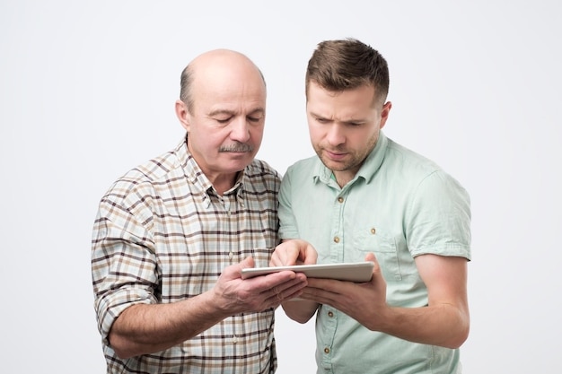 Zwei Männer, Vater und Sohn, surfen in einem Tablet