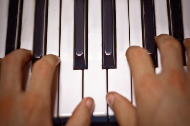 Foto zwei männliche hände auf dem klavier palmen liegen auf den tasten und spielen das tastaturinstrument in der musikschule schüler lernt zu spielen hände pianist schwarzer dunkler hintergrund top-ansicht