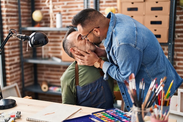 Zwei männliche Künstler zeichnen auf Notizbuch und küssen sich im Kunstatelier