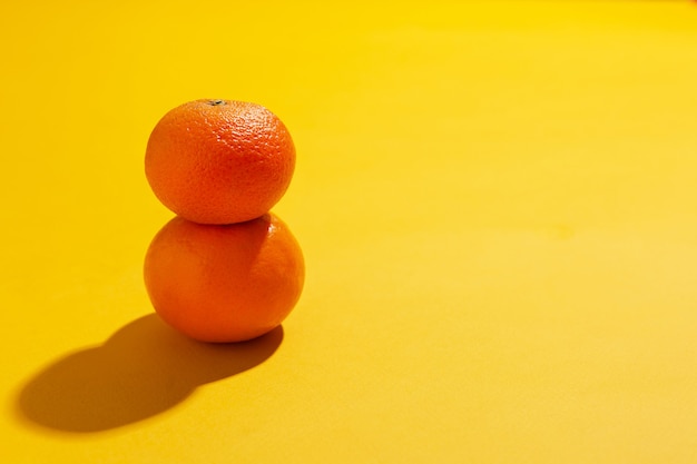 Foto zwei mandarinen mit blättern im stapel auf gelbem hintergrund