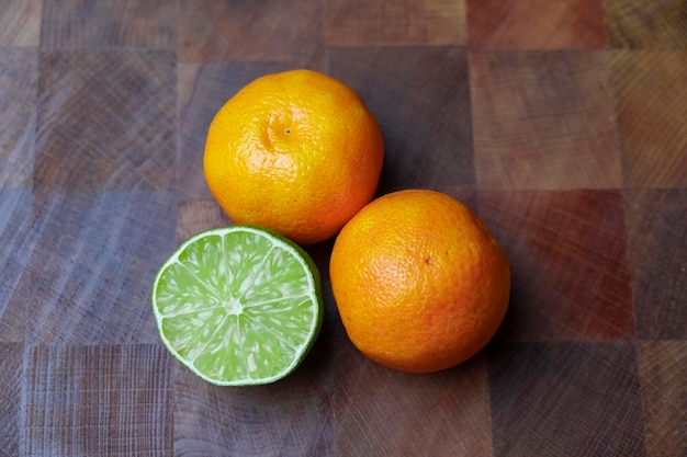 Zwei Mandarinen und Limetten auf Holztisch