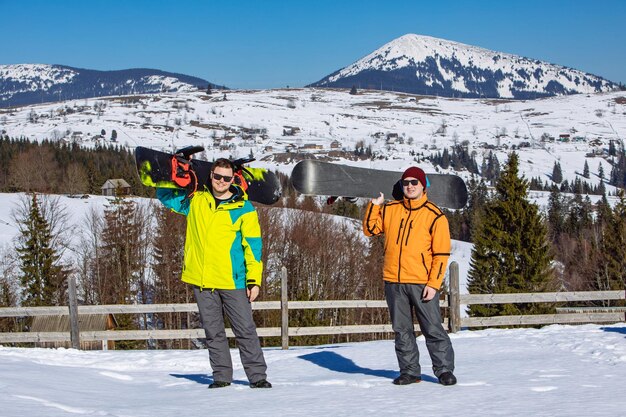 zwei Mann mit Snowboards Berge im Hintergrund Wintersport Lebensstil