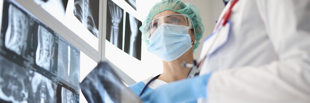 Zwei medizinische Mitarbeiter, die Schutzmasken tragen und Röntgenstrahlen betrachten