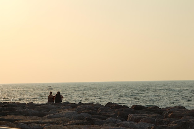 zwei Menschen stehen auf Felsen am Meer