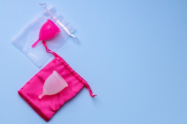 Zwei Menstruationstassen auf blauer Oberfläche, Draufsicht