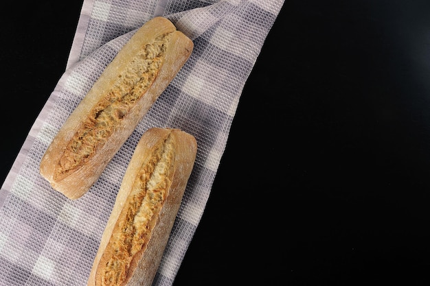 Zwei Mini-Baguettes auf schwarzem Hintergrund - französische Küche - Draufsicht flach gelegt