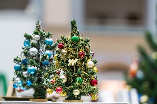 Zwei Miniatur-Spielzeug-Weihnachtsbäume mit blauem und rotem Dekor