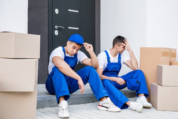 Zwei Mitarbeiter des Umzugsunternehmens machen eine Pause, während sie auf der Stufe sitzen