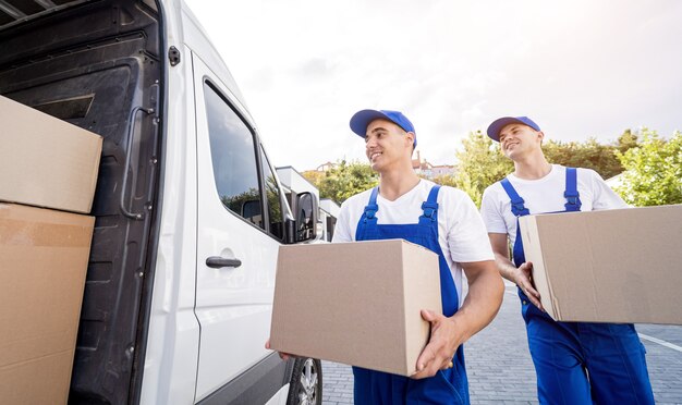 Zwei Mitarbeiter einer Umzugsfirma laden Kisten und Möbel in einen Kleinbus