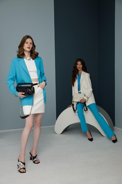 Zwei Models in Aquablau-Weiß sehen Jacke Blazer Rock Top Hose Hose Handtasche aus