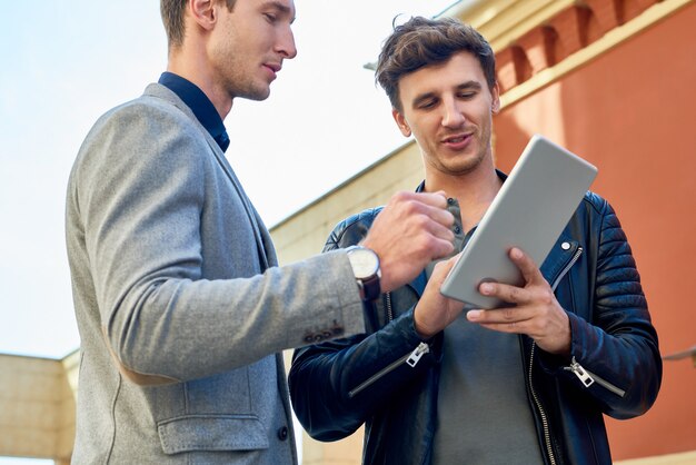 Zwei moderne geschäftsleute, die digitales tablett im freien verwenden